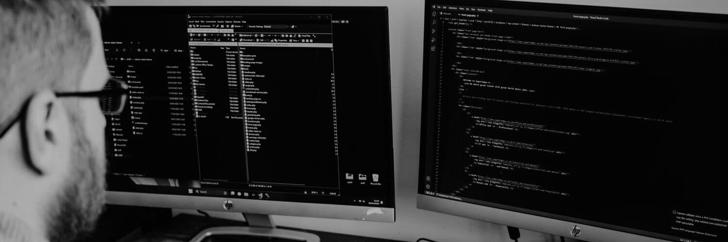 A builder at a two monitor desk with code open on both screens.